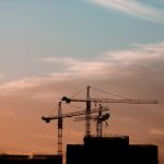 建設業の夏季休工を解説する記事のアイキャッチ。夕暮れの建設現場とクレーンのイメージ